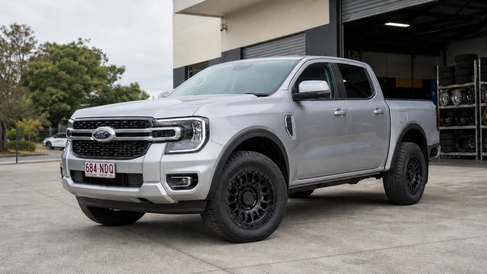 Silver Next-Gen Ford Ranger fitted with matte-black KMC wheels outside a Brisbane tyre workshop