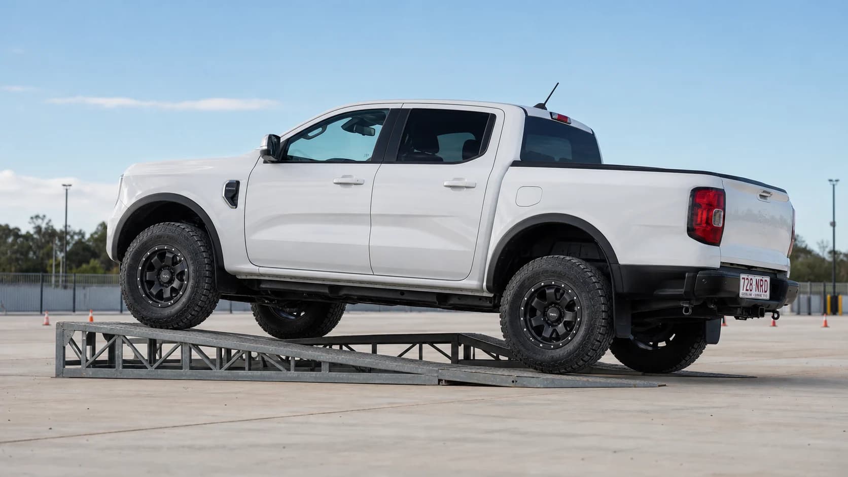 White Next-Gen Ford Ranger on 33-inch-class all-terrain tyres parked on steel articulation ramps in Queensland