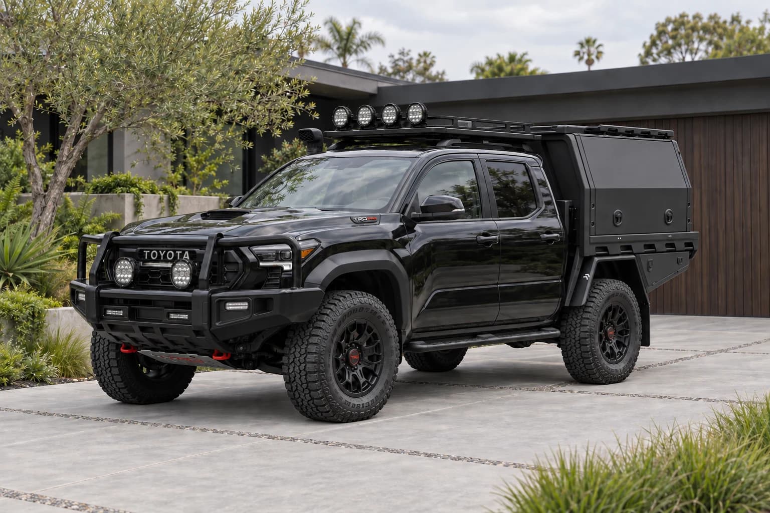 Black Toyota Tacoma accessory concept with a MITS canopy, front protection and roof equipment