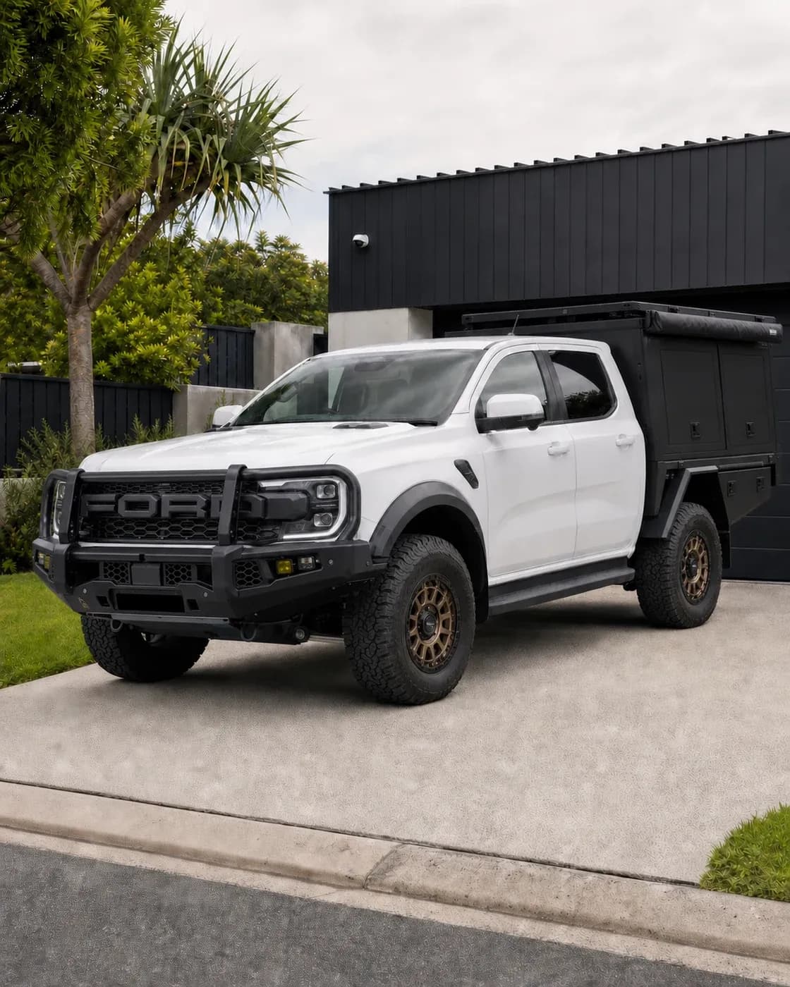 The same white Ford Ranger Raptor with a bull bar, touring canopy, roof rack, awning and bronze wheels