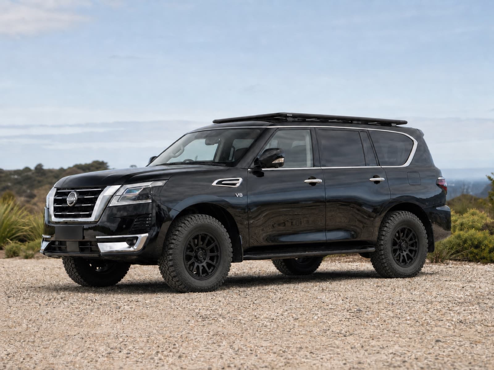 Black Nissan Patrol Y62 with a Rhino-Rack Pioneer platform and off-road wheels
