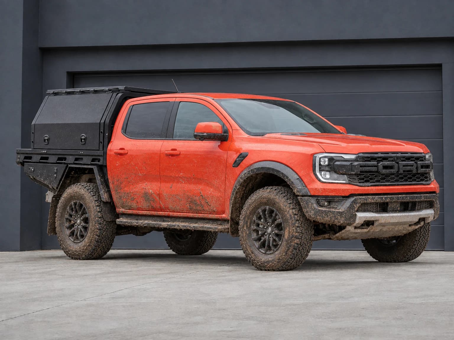 Orange Ford Ranger Raptor visualisation with a black tray and canopy and mud across the lower body and tyres
