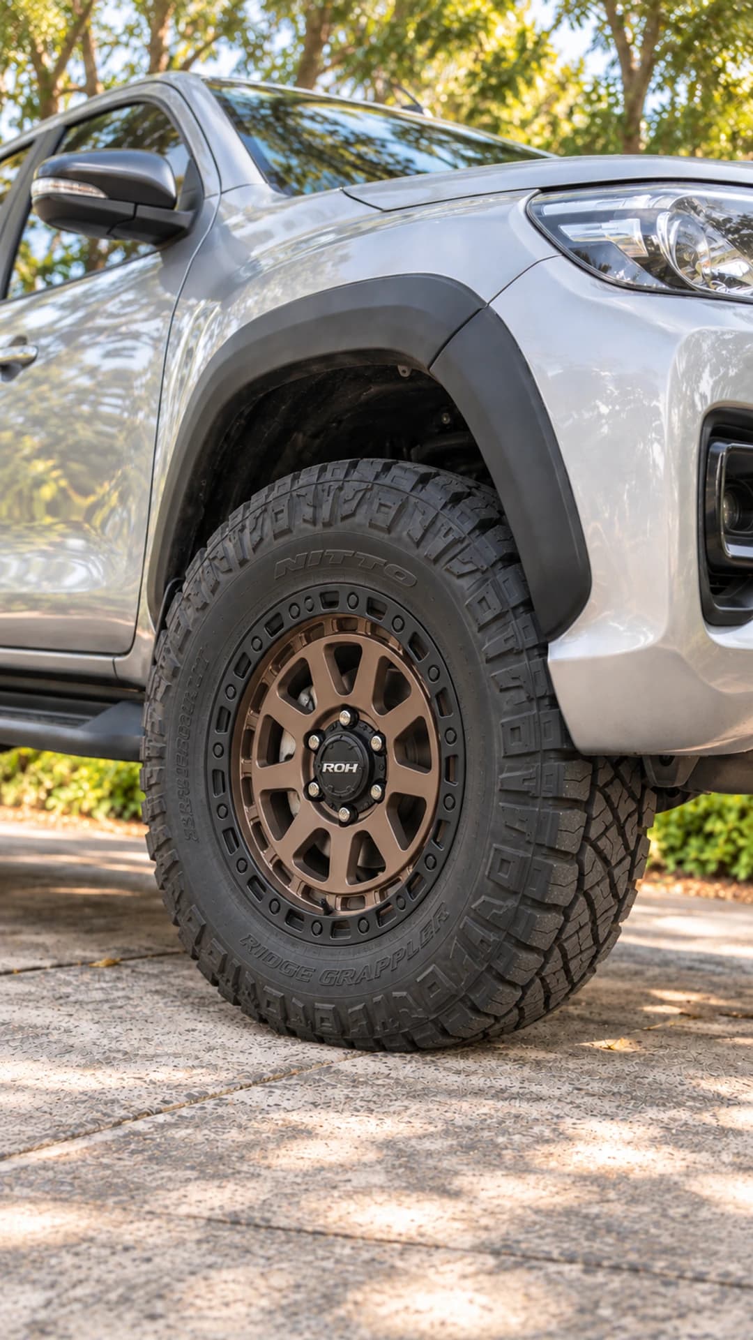 Close-up of a bronze ROH Assault wheel and off-road tyre on a silver Toyota HiLux N80