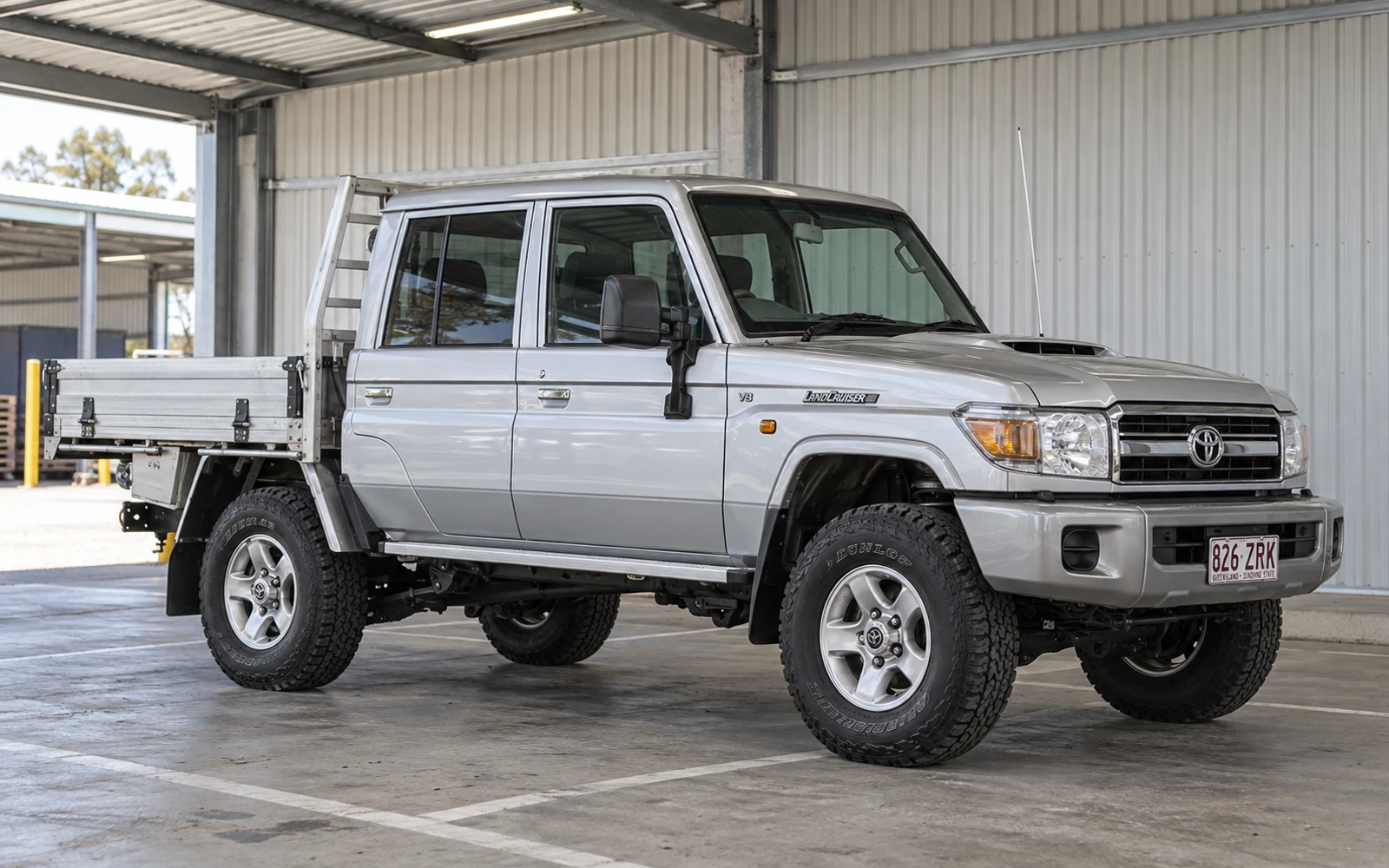 Silver Toyota LandCruiser 79 Series dual cab with an alloy tray parked in a workshop